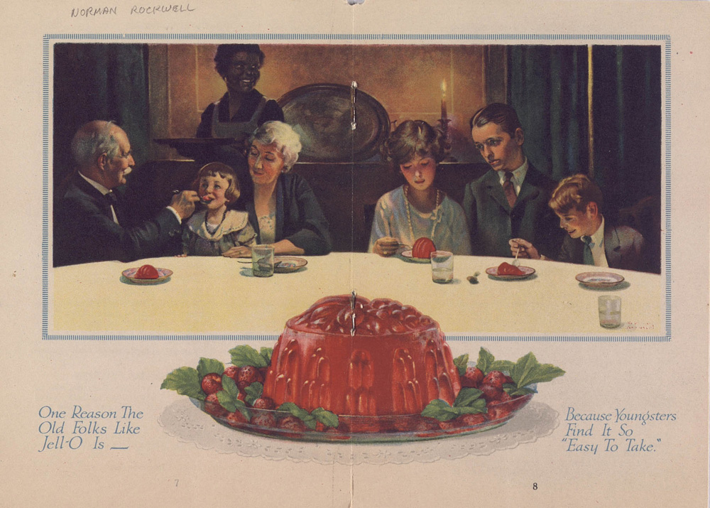 A family in 1920’s clothing sits around a table eating red jell-o, with a waitress in a white apron behind them. A large red jell-o mold garnished with strawberries is in the foreground