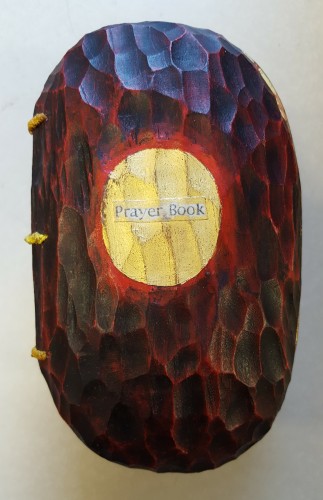 Closed egg-shaped cherrywood book reading "Prayer Book" on the cover