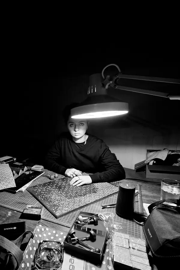 Black and white photo of Stephanie Osorio sitting at a craft work table