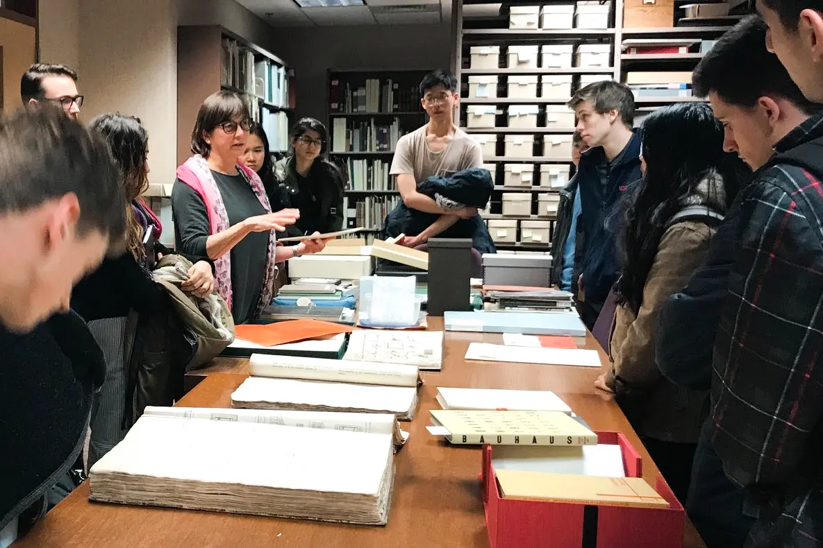 Librarian with a group of students around a table looking at materials.