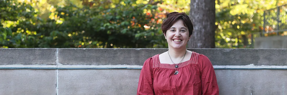 Woman in a red shirt in front of a concrete wall.