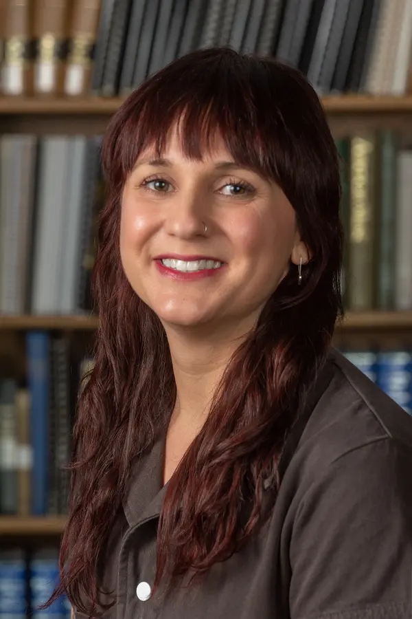 Photo of Bridget Kennedy, woman with long dark brown hair, wearing a brown top, smiling at camera.