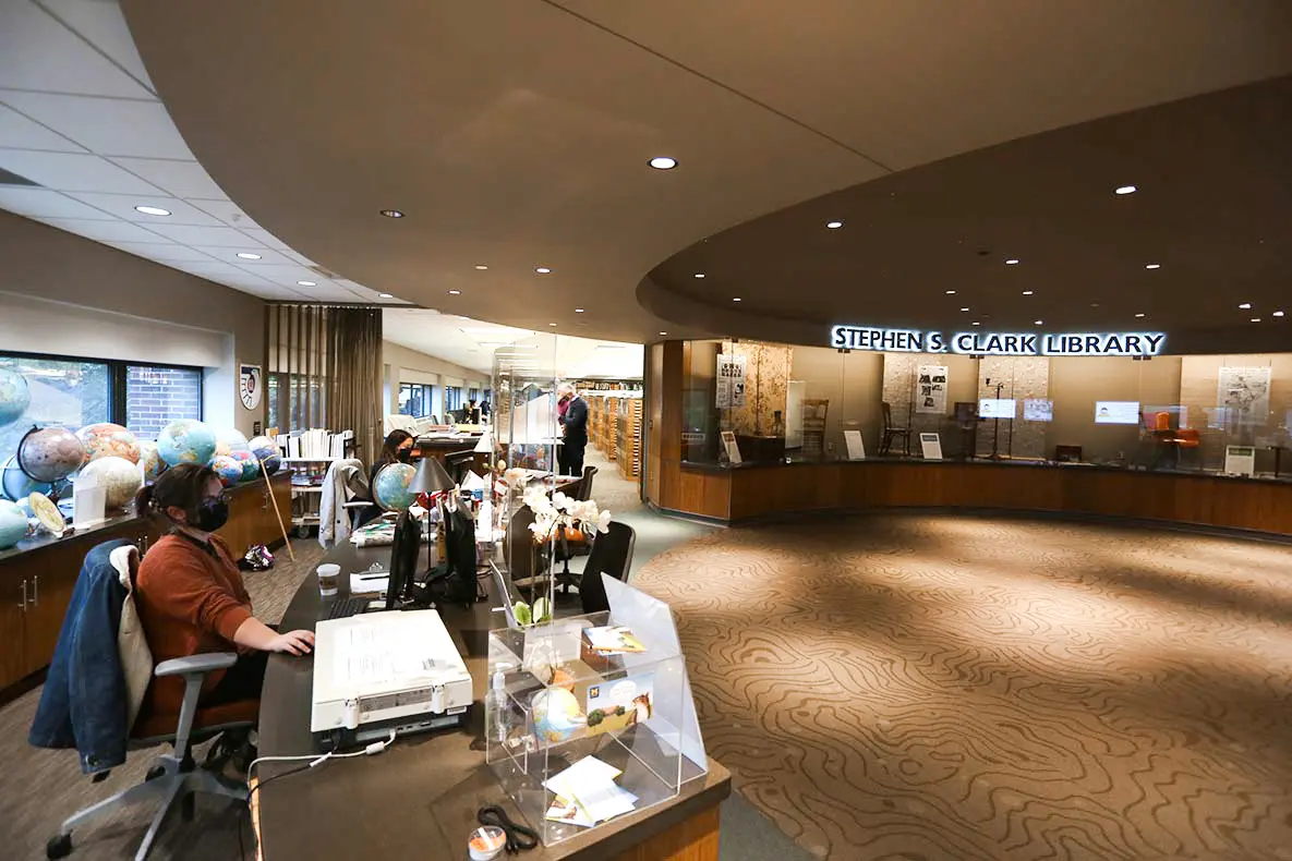 Clark Library Desk with employees sitting at it and a view a of the exhibit case.
