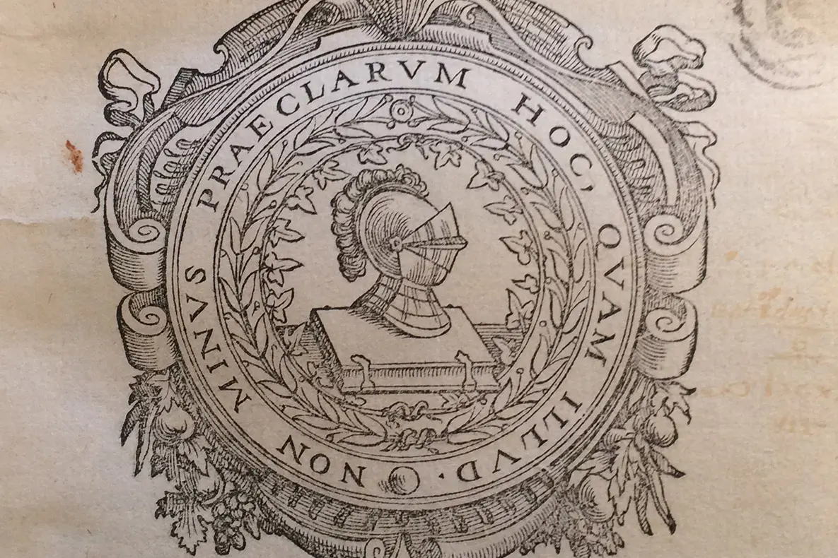 Drawing of a knight's helmet on top of book surrounded by an ornate frame.