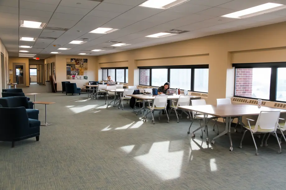 Open space with tables along the windows and a few students studying.