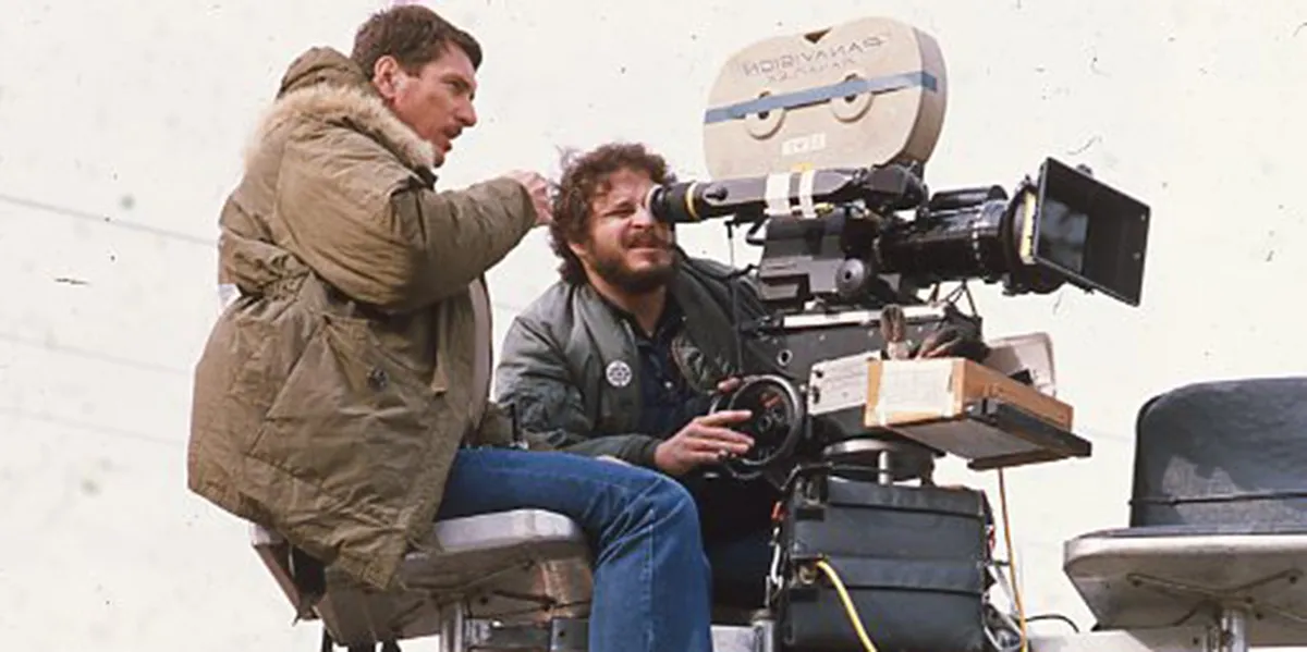 Photograph of Lawrence Kasdan looking into a camera on a movie set.