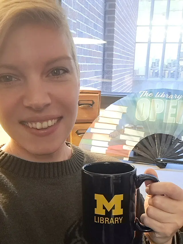 Photo of librarian Beth Havas, smiling and holding a University of Michigan Library mug.