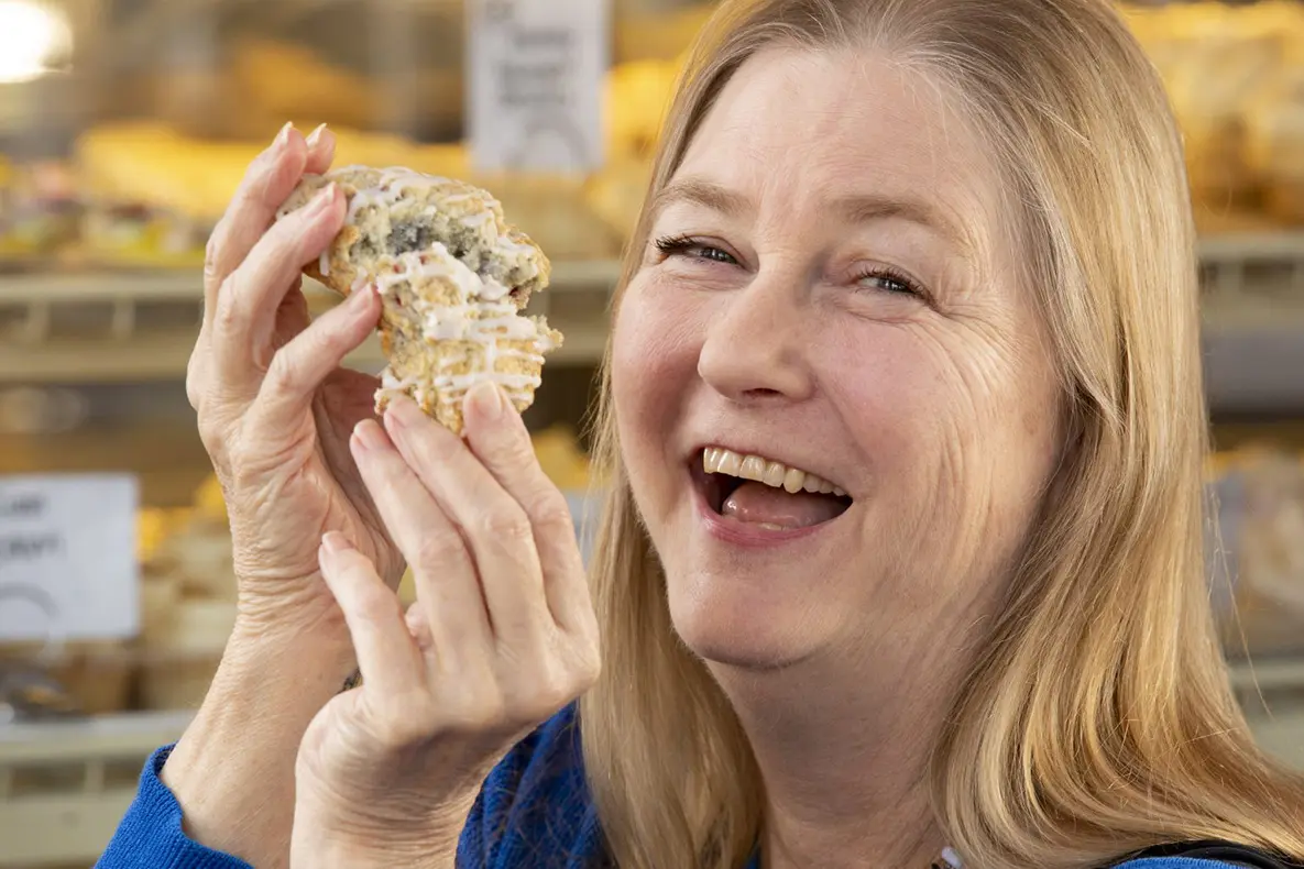 Woman breaking a large scone in half.