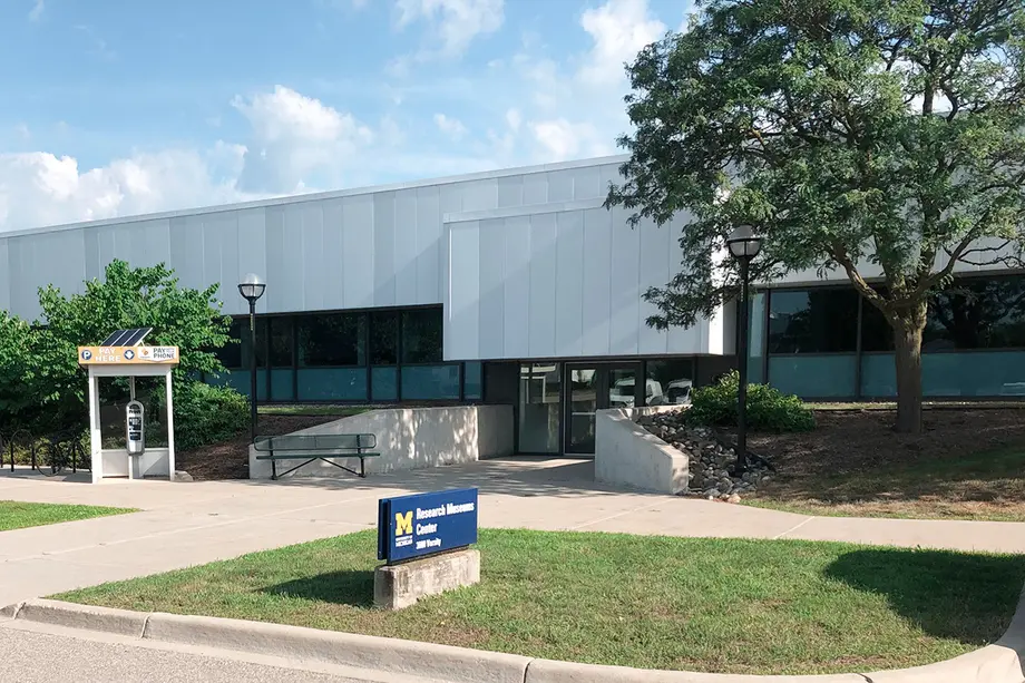 Exterior of the Research Museums Center with building sign, parking pay machine, and entrance.