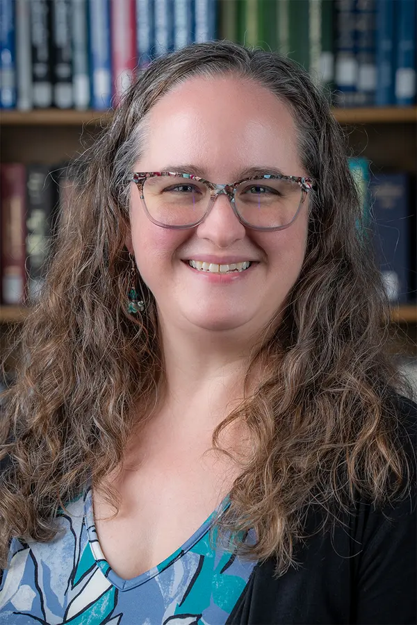 Photo of Sara Samuel, a white woman with long wavy light brown hair and glasses.