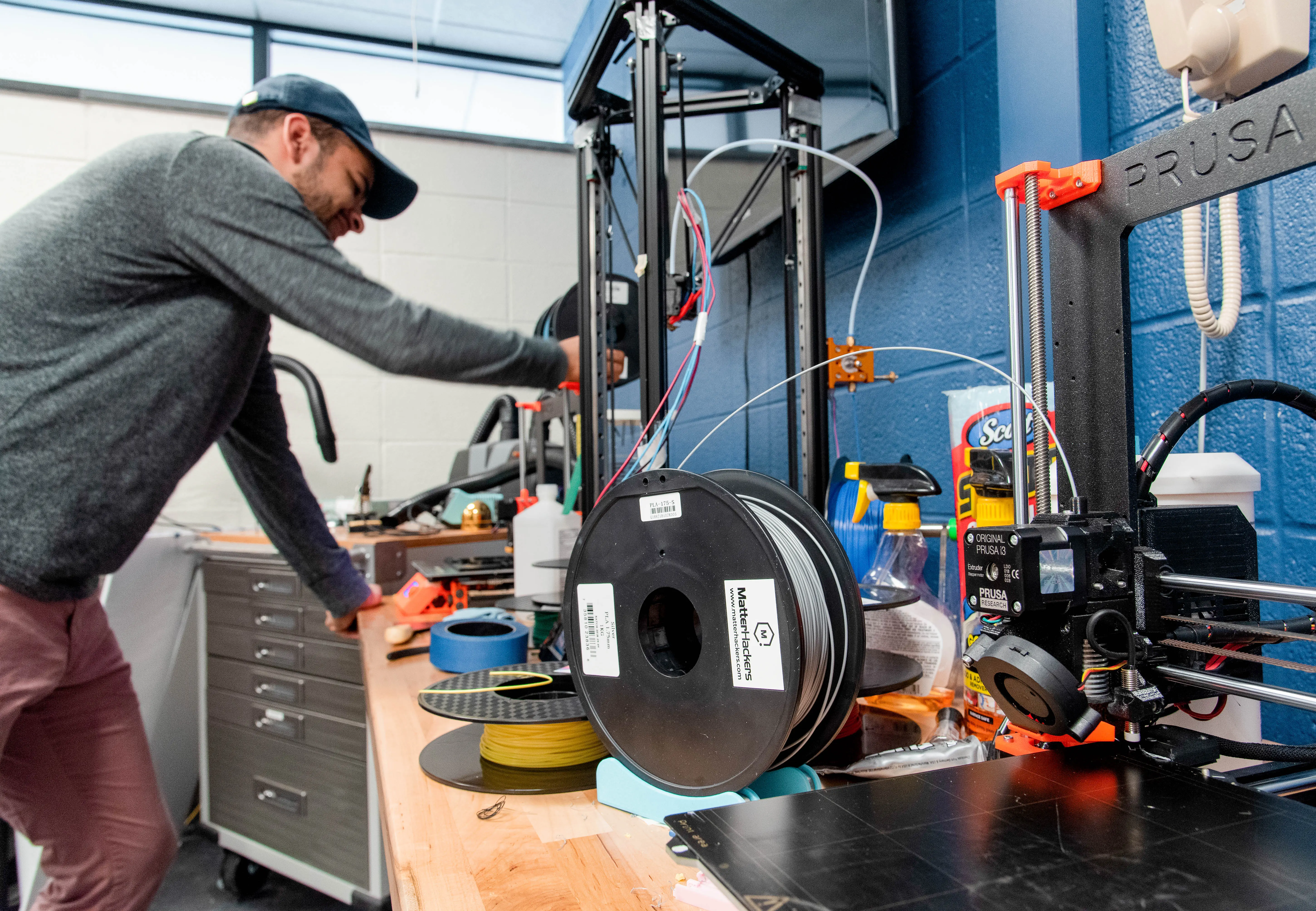 Student at a workbench that is covered with a variety of hardware and materials.