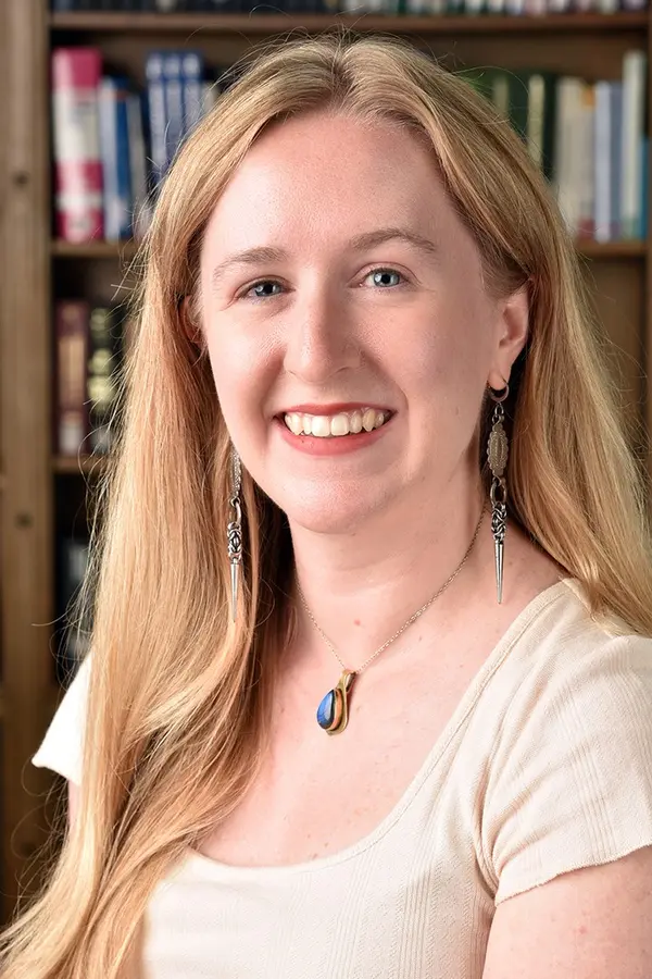 Headshot of Lauren Stachew smiling in a cream-colored shirt, with bookshelves in the background