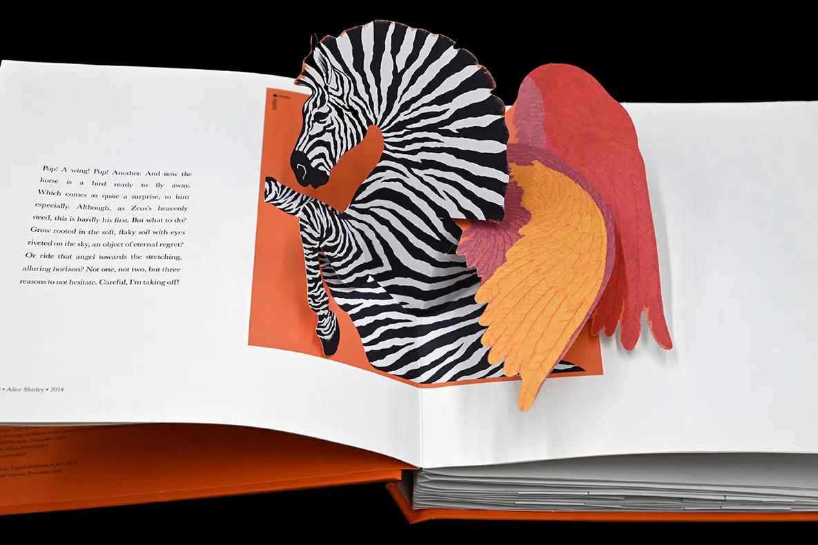 A zebra with red and orange feather wings popping out from the spine of a book.