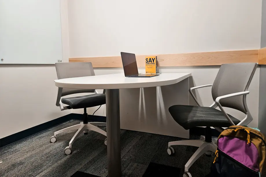 Small table with two office chairs and wall-mounted whiteboard.