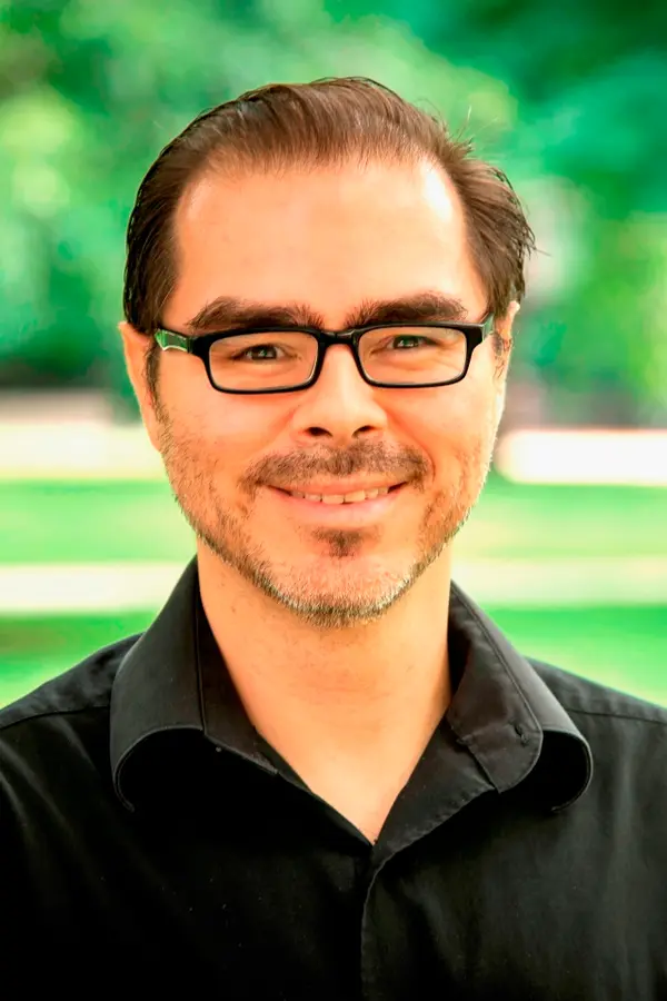 Photograph of Gabriel Duque, a Latino man wearing glasses and a black shirt. 