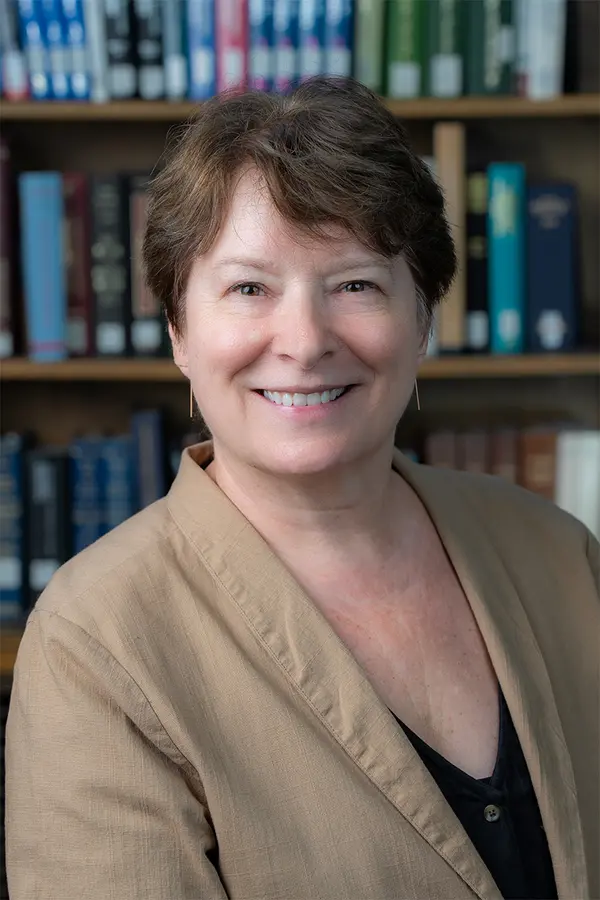 Smiling woman with short dark brown hair and wearing a light brown blazer.