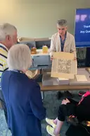 A curator showing up a rare manuscript to donors.