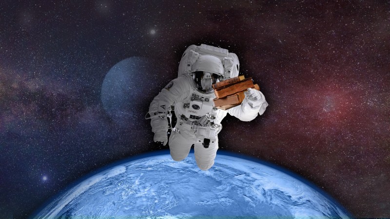astronaut in space holding old books with earth in the background