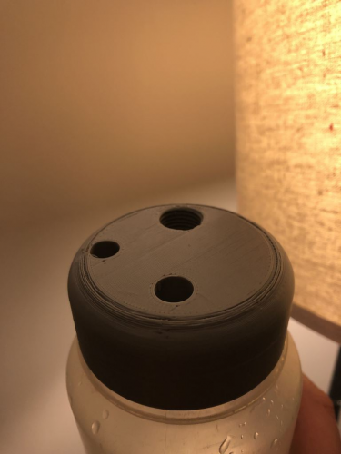 A 3D-printed black water bottle cap with three holes. 