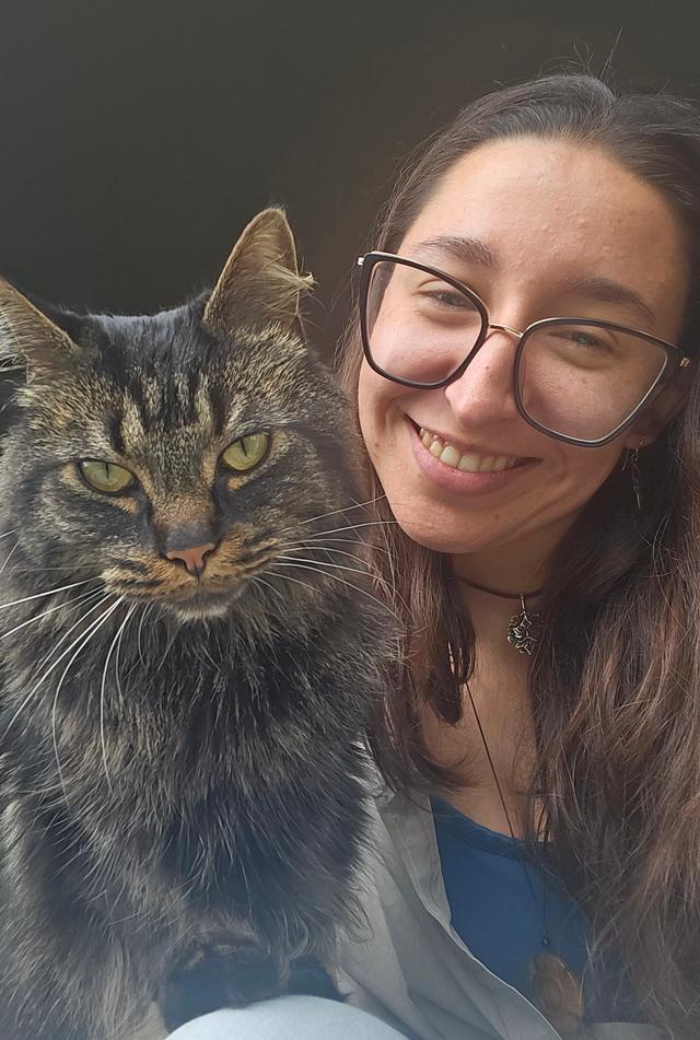 Brown-haired Latina woman smiling with black and brown tabby cat