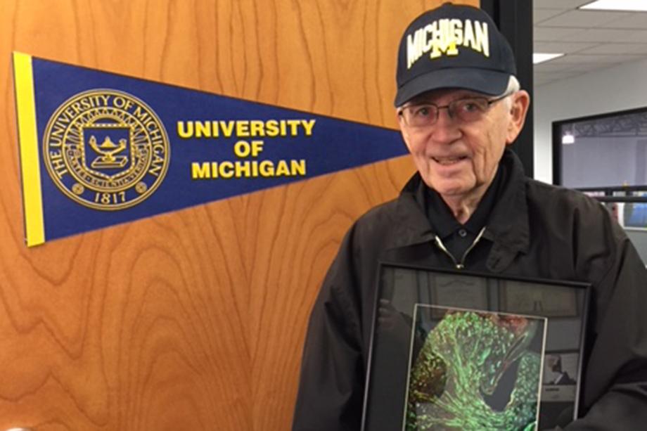 Arnold Heyman standing next to a University of Michigan banner.