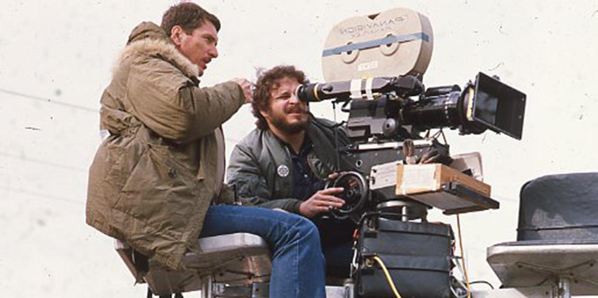 Photograph of Lawrence Kasdan looking into a camera on a movie set.