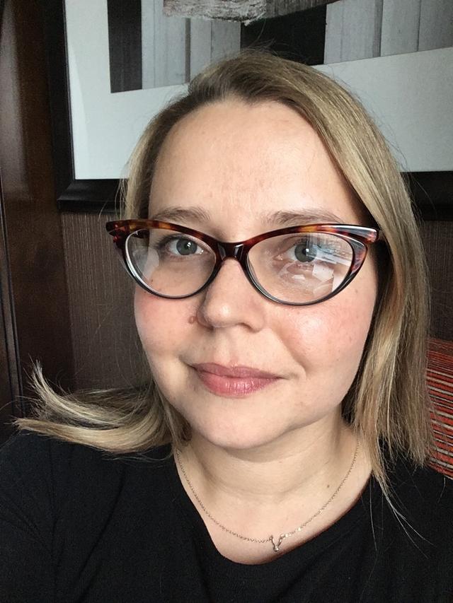 Photo of Kate Saylor, a white woman with medium length blonde hair, and glasses.