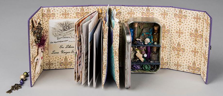 Book standing open and showing fancy endpapers, ragged pages, and an open box of treasures that includes a skull.