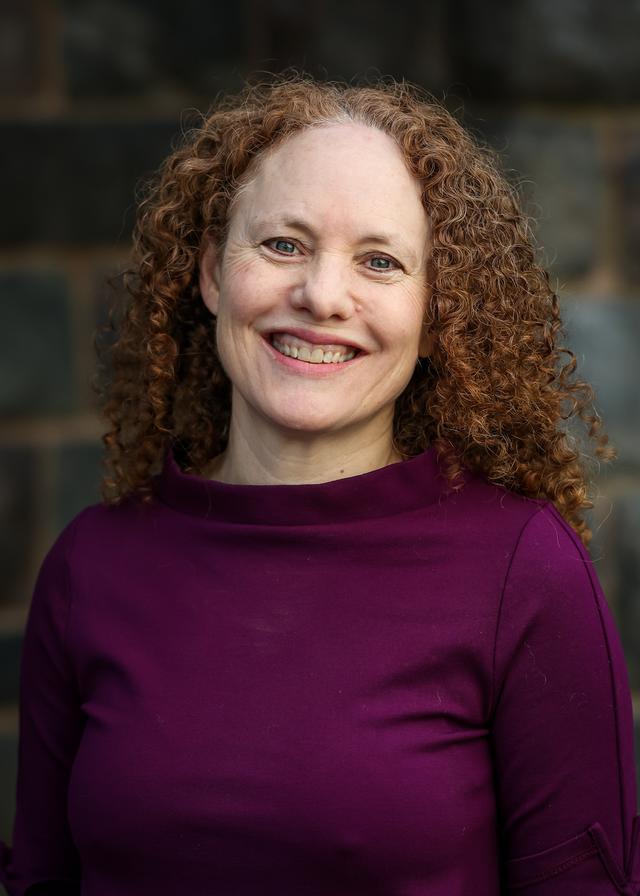 Image of female with curly red hair smiling at the camera. 