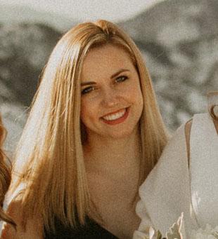 Headshot of Joan Kwaske, a woman in her mid-twenties with long blonde hair, smiling at the camera.