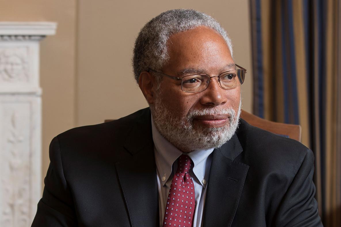 Black man wearing glasses and a red tie.