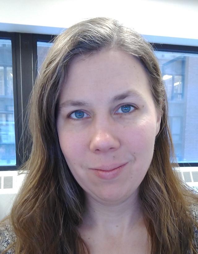 Photograph of Nicole Scholtz, a white woman with long wavy brown hair, in front of a window