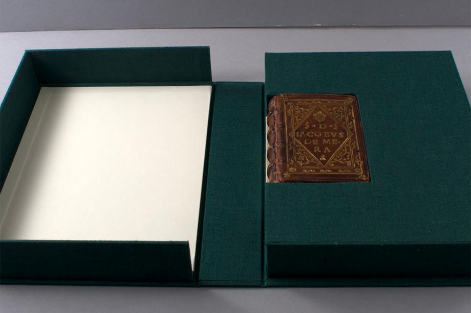 green protective box opened to show a small brown leather-bound book