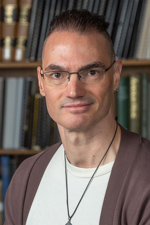 Photo of Scott Martin: a white man with glasses, in front of a shelf of books