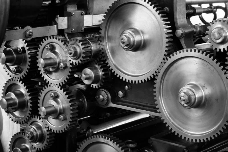 Black and white image of many cogs turning together.
