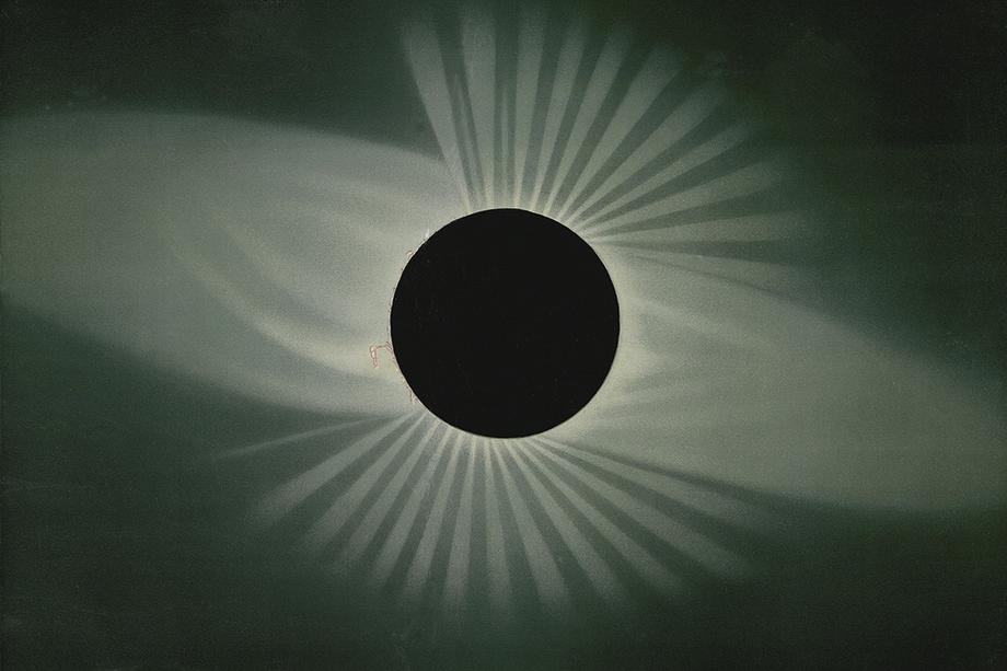 Black circle moon with rays of sun shining out from behind it.