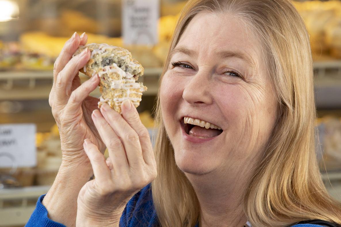 Woman breaking a large scone in half.