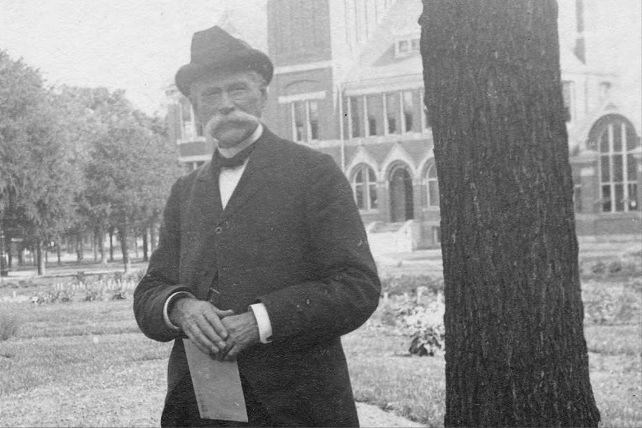 man wearing a hat standing next to a tree