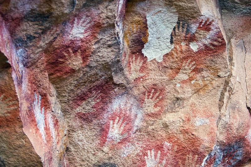 Ancient cave paintings with visible hand prints.