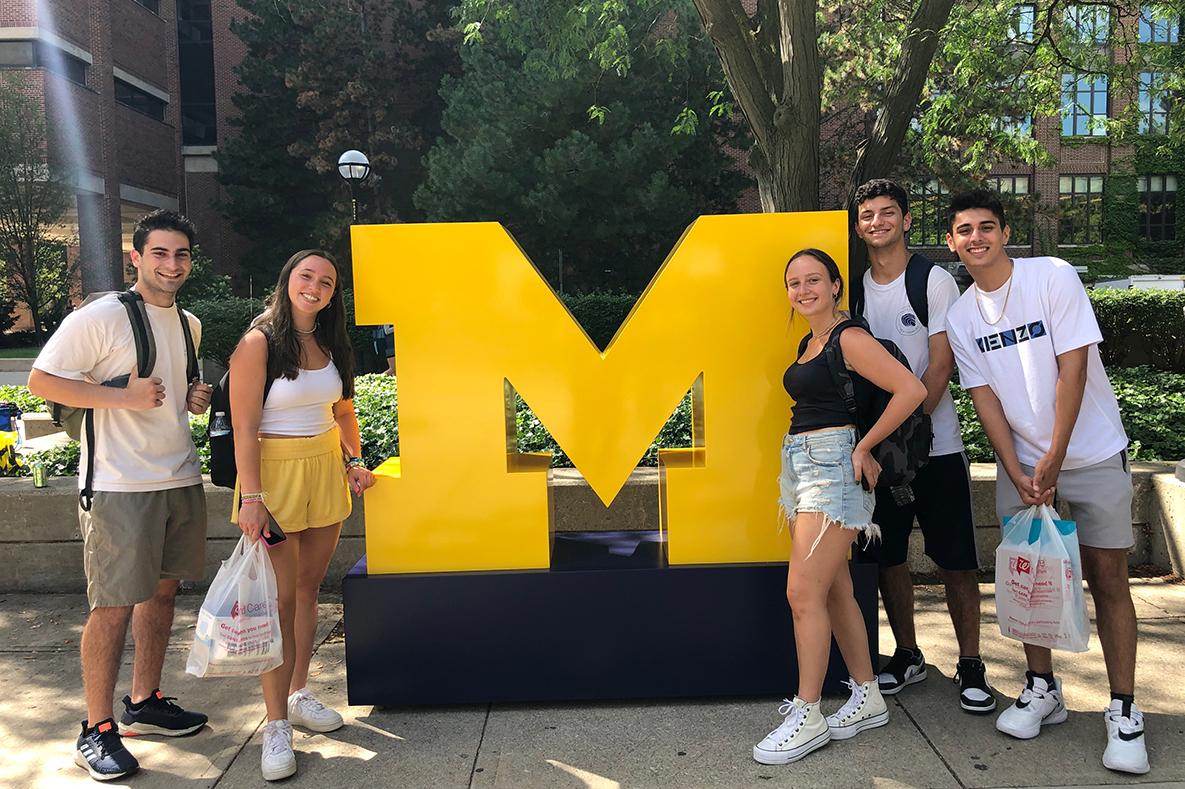 Students standing beside a giant block M.