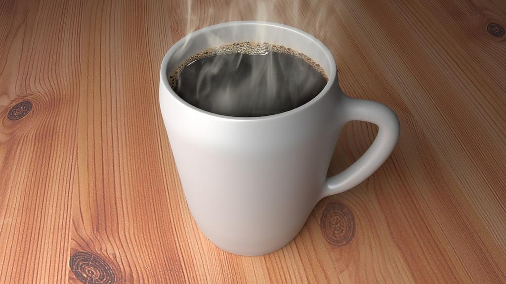 Steaming cup of coffee in a white mug on a wood tabletop.