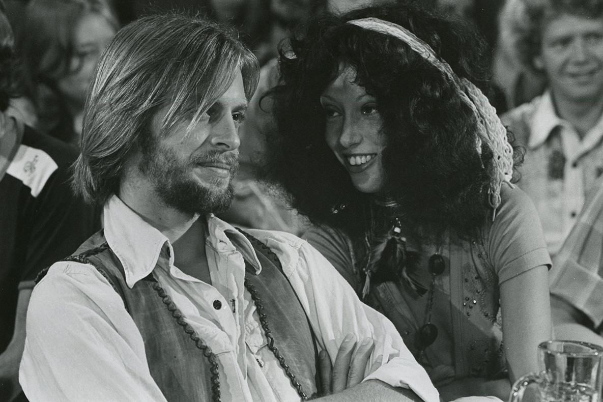 A man stares straight ahead while the woman sitting next to him is turned toward him and looking at him.