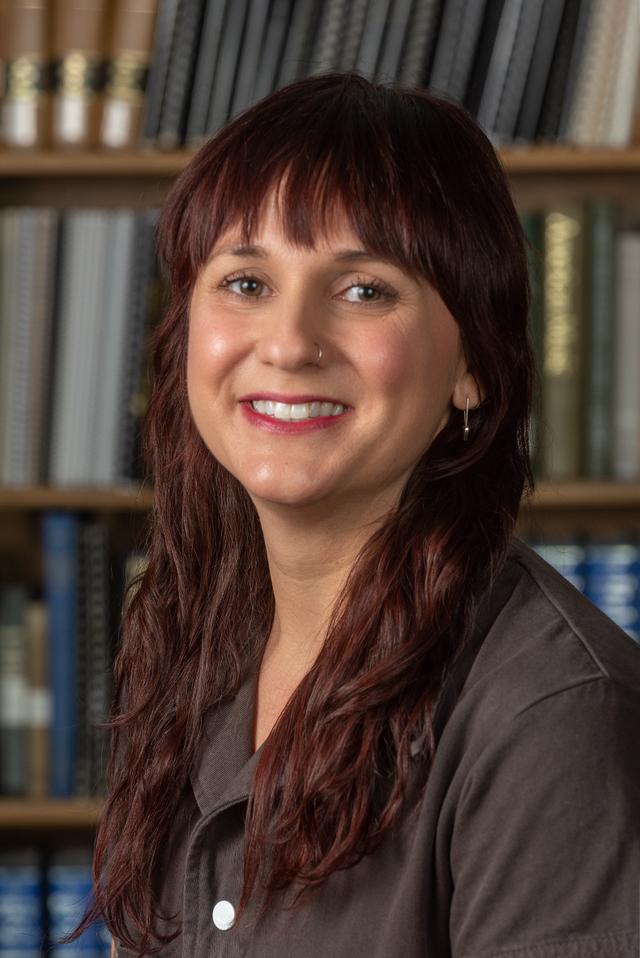 Photo of Bridget Kennedy, woman with long dark brown hair, wearing a brown top, smiling at camera. 