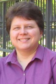 Photograph of Helen Koustova, a white woman with short brown hair wearing a magenta blouse