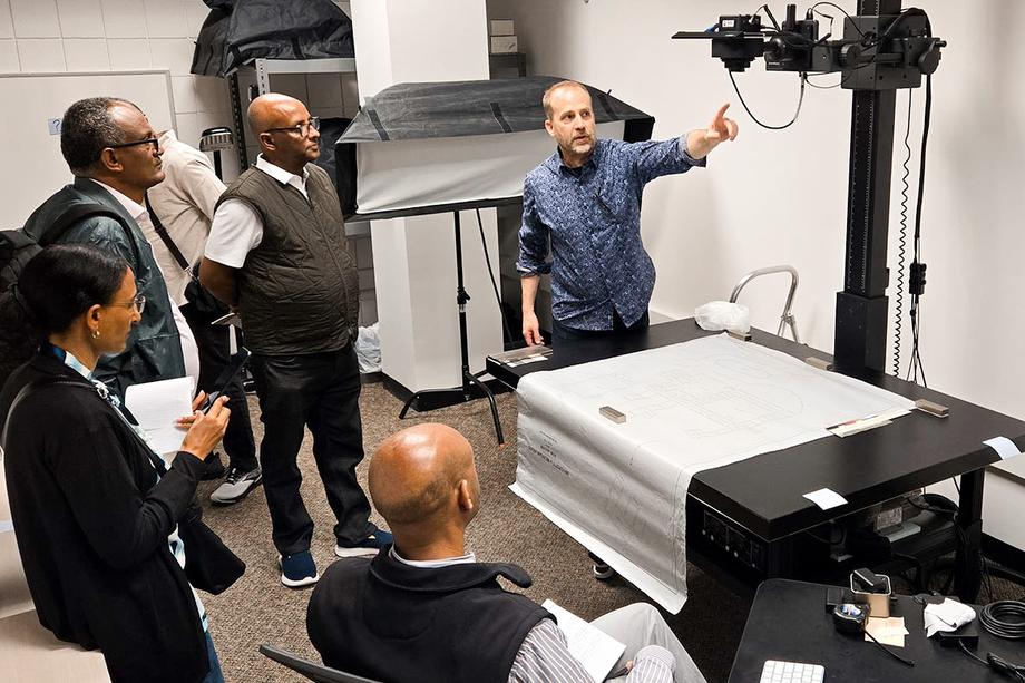 A DCU employee demonstrating using a digital camera and copy stand during a tour.