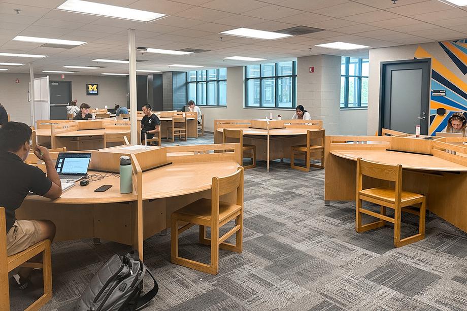 Round tables separated by partitions into individual work areas with windows in the background.